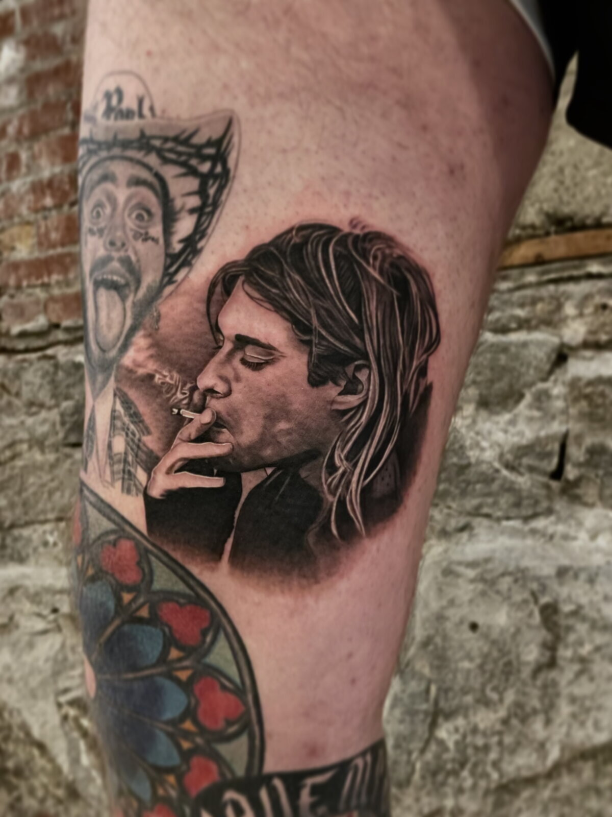 Black and grey realism portrait tattoo of a musician smoking, upper leg